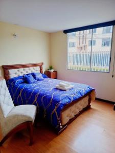 a bedroom with a bed with a blue comforter and a window at Spacious private rooms close to American Embassy in Quito +8 photos