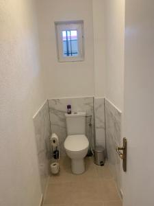 a white toilet in a bathroom with a window at Appartement en face de la gare de St-Louis in Saint-Louis