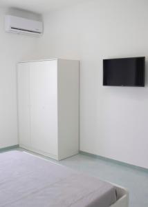 Un dormitorio blanco con una cama y un televisor de pantalla plana. en Home24, en Casalnuovo di Napoli