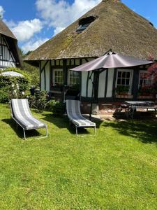 two chairs and an umbrella in front of a house at Le manège du silence in Bénesville