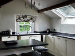 a kitchen with white cabinets and a sink and a window at Penthouse apartment in Cockermouth +3 photos