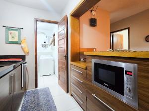 a kitchen with wooden cabinets and a television in it at Ap 2 quartos e varanda na Borges próximo R Coberta in Gramado