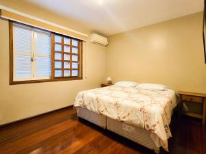 a bedroom with a bed and a large window at Ap 2 quartos e varanda na Borges próximo R Coberta in Gramado