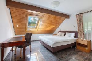 a bedroom with a bed and a desk and a window at Amadeus Black Forest Mountain in Todtmoos