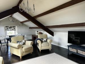 a living room with two chairs and a tv at Penthouse apartment in Cockermouth