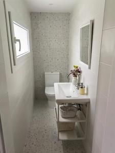 a white bathroom with a sink and a toilet at Casinha do Chico in Charneca +50 photos