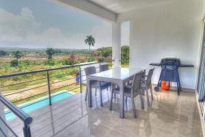 a dining room with a table and chairs on a balcony at 2 Bedroom Pool Villa in Gated Encuentro Residences by Palm Hills Real Estate in Cabarete