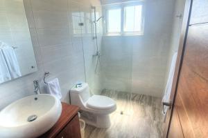 a white bathroom with a toilet and a sink at 2 Bedroom Pool Villa in Gated Encuentro Residences by Palm Hills Real Estate in Cabarete +5 photos