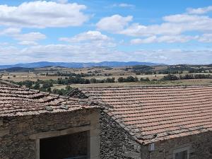 an old stone building with tile roofs with mountains in the background at A Toca dos Coelhos in Mogadouro