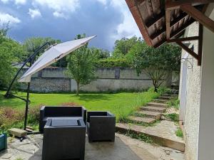 a patio with two chairs and an umbrella at La petite maison in Sainte-Gemme-Moronval +12 photos