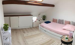 a white bedroom with a bed and a table at La petite maison in Sainte-Gemme-Moronval