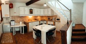 a kitchen with white cabinets and a table and a staircase at La petite maison in Sainte-Gemme-Moronval