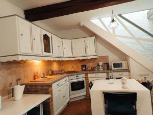a kitchen with white cabinets and an attic at La petite maison in Sainte-Gemme-Moronval