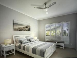 Goolwa SouthGoolwa Serenity - Modern, Peaceful, Linen & wifi included的一间卧室配有一张带吊扇和窗户的床。