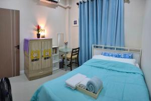 a bedroom with a blue bed with a desk and a chair at โฮมสเตย์บ้านญาติมุกดาหาร in Ban Muang Ba