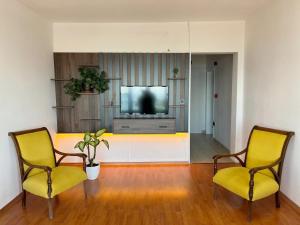 Sala de estar con 2 sillas amarillas y TV en Sapanca Albar Konaklama, en Sapanca
