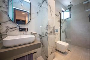 a bathroom with a sink and a toilet and a mirror at Vila Olserd Shehu in Ksamil