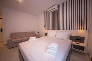 a bedroom with a bed with white sheets and a couch at Vila Olserd Shehu in Ksamil