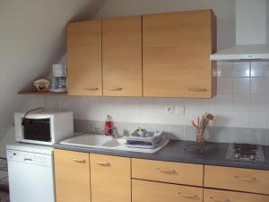 a kitchen with wooden cabinets and a sink and a microwave at Villa Le Clos de Mosny in Amboise