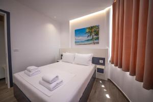 a white bedroom with a bed with towels on it at Vila Olserd Shehu in Ksamil