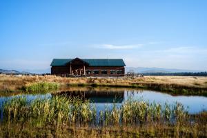 een huis in het midden van een veld met een vijver bij Bar N Ranch in West Yellowstone