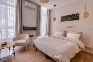 une chambre avec un grand lit blanc et une chaise dans l'établissement Short Time Suites Toulon Centre 1 "LE STUDIO" Check-in auto, à Toulon