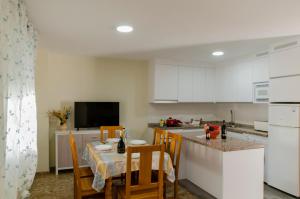 a kitchen with white cabinets and a table with chairs at El Atico de Andrea in Torre del Mar