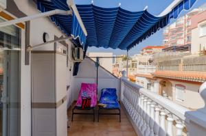a balcony with two chairs and a blue awning at El Atico de Andrea in Torre del Mar +7 photos