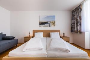 a bedroom with a white bed and a blue couch at Urbanihof in Jois in Jois