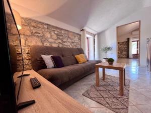 a living room with a brown couch and a stone wall at Stone House Mia in Premantura