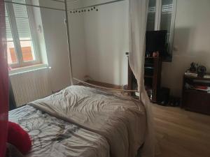 an unmade bed in a bedroom with a curtain at Maison centre-ville in Capdenac-Gare