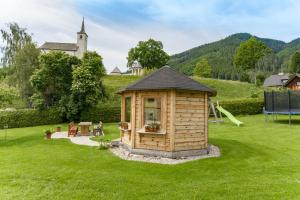 a wooden cabin in the grass with a playground at Haus König in Mauterndorf