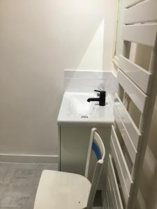 a white bathroom with a sink and a chair at 10 Porte Cadre in Rochefort-en-Terre +1 photo