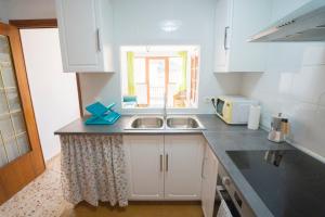 a kitchen with white cabinets and a sink and a window at House Los Angeles in Chulilla +10 photos