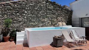 una piscina con 2 sillas y una pared de piedra en Casa del Aire, en Aldea de Trujillo 54 fotos más