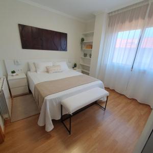 Un dormitorio blanco con una cama grande y una ventana. en MARALES Sanxenxo, en Sanxenxo