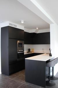 a kitchen with black cabinets and a white counter top at koetshuis in Ieper