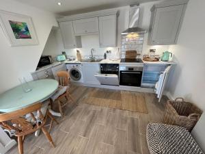 a kitchen with white cabinets and a table and chairs at The Cottage - Snowdonia, North Wales in Bethesda
