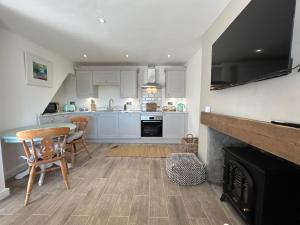 a kitchen with white cabinets and a fireplace at The Cottage - Snowdonia, North Wales in Bethesda
