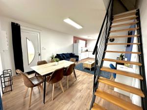 a room with a table and chairs and a staircase at L'Équinoxe - Parking privé - Cocoplume Suites in Malesherbes