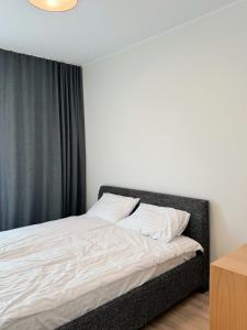 a bed with white sheets and a black curtain at Dainas Apartment in Rīga +64 photos