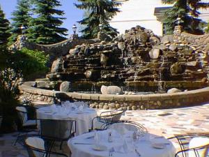 una mesa con mesas y sillas blancas frente a una fuente en Mario's International Spa, Hotel & Restaurant, en Aurora