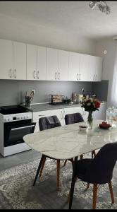 une cuisine avec une table avec des chaises et des armoires blanches dans l'établissement Apartment BORICI, à Bihać