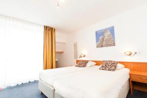 a hotel room with two beds and a window at Hotel de Burg in Domburg