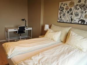 a bed in a bedroom with a desk and a chair at New and fresh apartment, free parking and ocean view in Trondheim