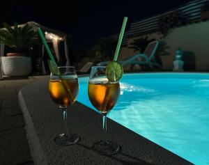 two wine glasses sitting next to a swimming pool at Holiday Home Villa Romantica in Sveti Filip i Jakov