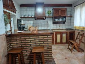 a kitchen with a brick counter and wooden stools at Como en casa in Alcaracejos
