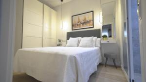 a white bedroom with a large bed with white sheets at Casa Pescadores Torrevieja in Torrevieja