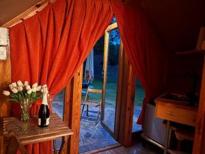 a bottle of wine on a table with a vase of flowers at Bungalow Bay Łacha in Łacha