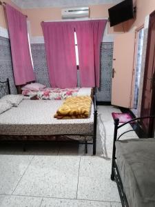 a bedroom with two beds and pink curtains at La Perle in Meknès